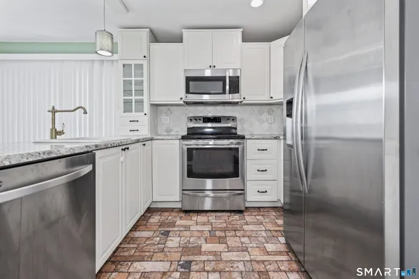 a kitchen with stainless steel appliances granite countertop a stove a refrigerator and a sink