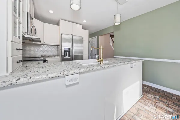a kitchen with stainless steel appliances granite countertop a sink and a refrigerator
