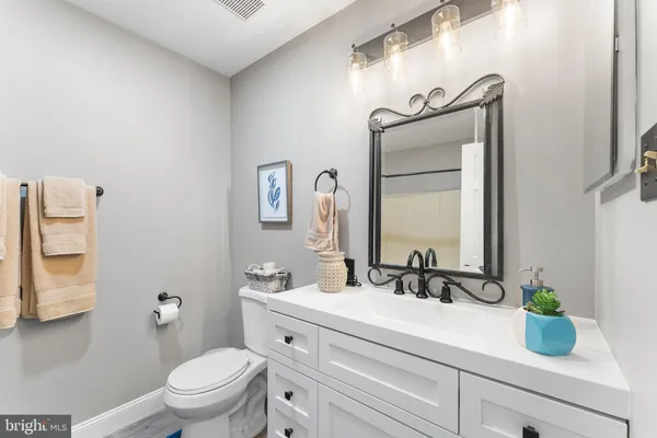 a bathroom with a granite countertop sink vanity mirror and toilet