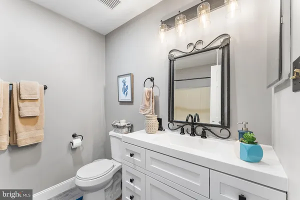 a bathroom with a granite countertop sink vanity mirror and toilet