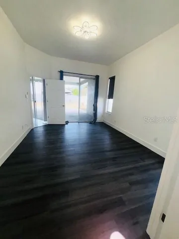 a view of an empty room with a window and wooden floor