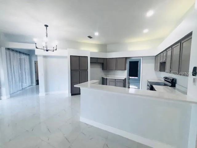 a large white kitchen with a stove a sink dishwasher and a refrigerator with wooden floor