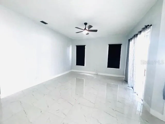 an empty room with windows and fan