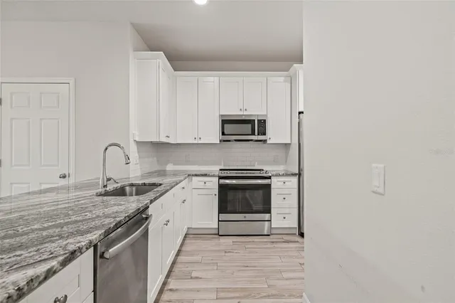 a kitchen with granite countertop white cabinets and stainless steel appliances