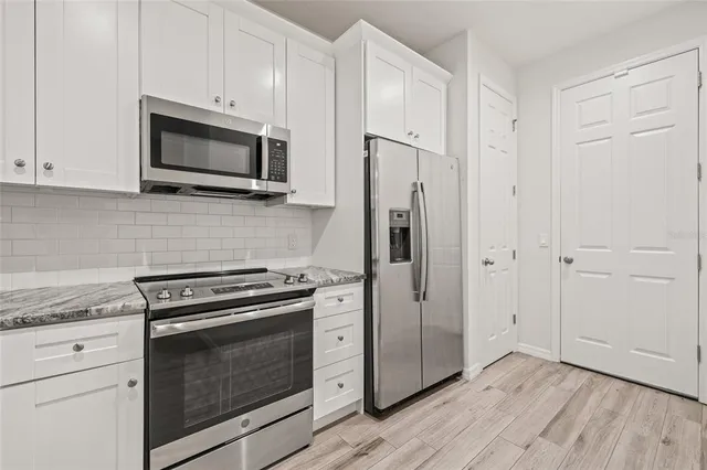 a kitchen with stainless steel appliances white cabinets white stove a microwave and a refrigerator