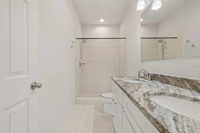 a bathroom with a granite countertop sink a toilet and shower