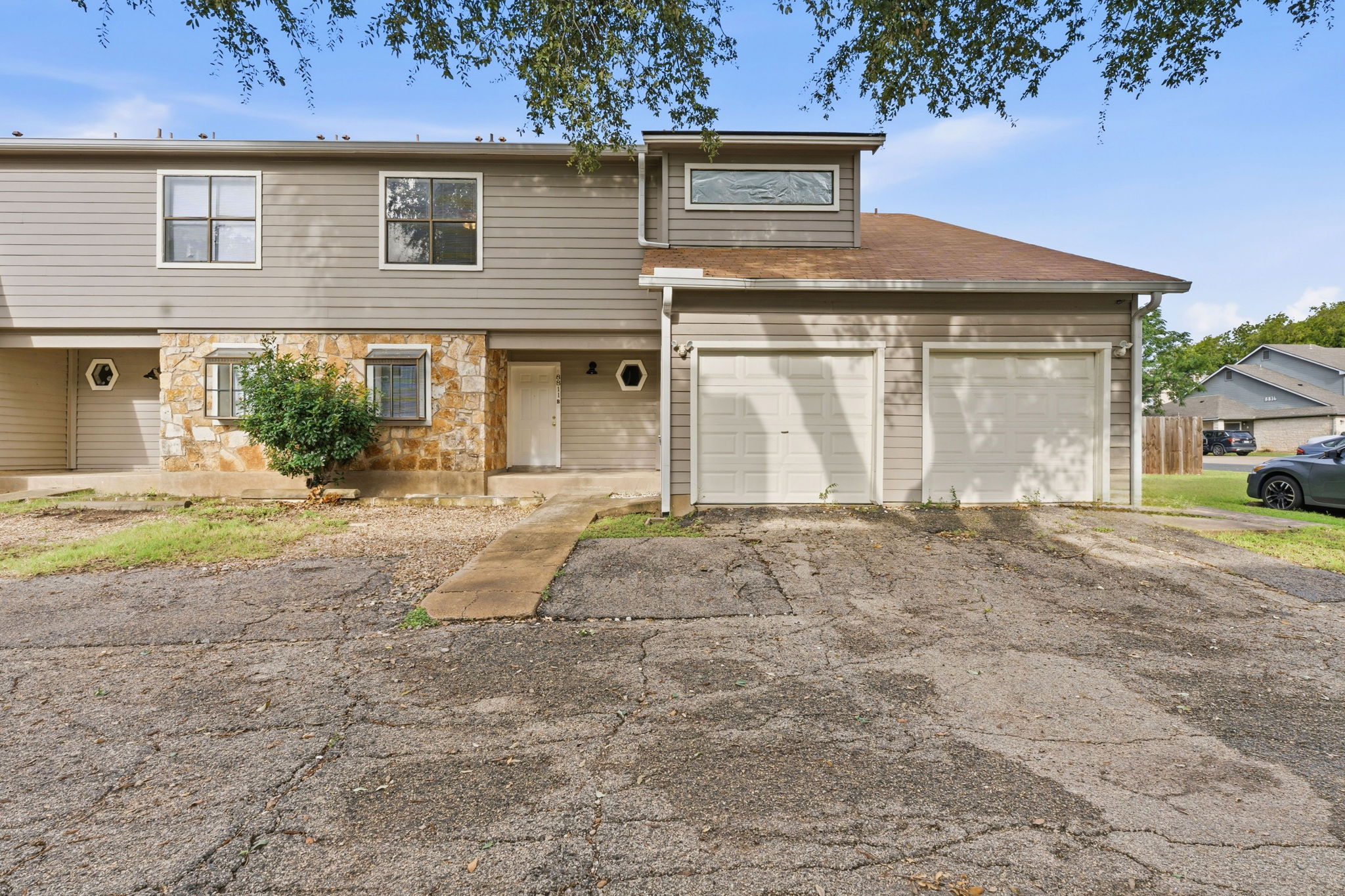 8811 Schick Road Austin, TX 78729 - Photo 5 of 27 A well-maintained facade features stone accents, multiple entry points, and convenient attached garages.