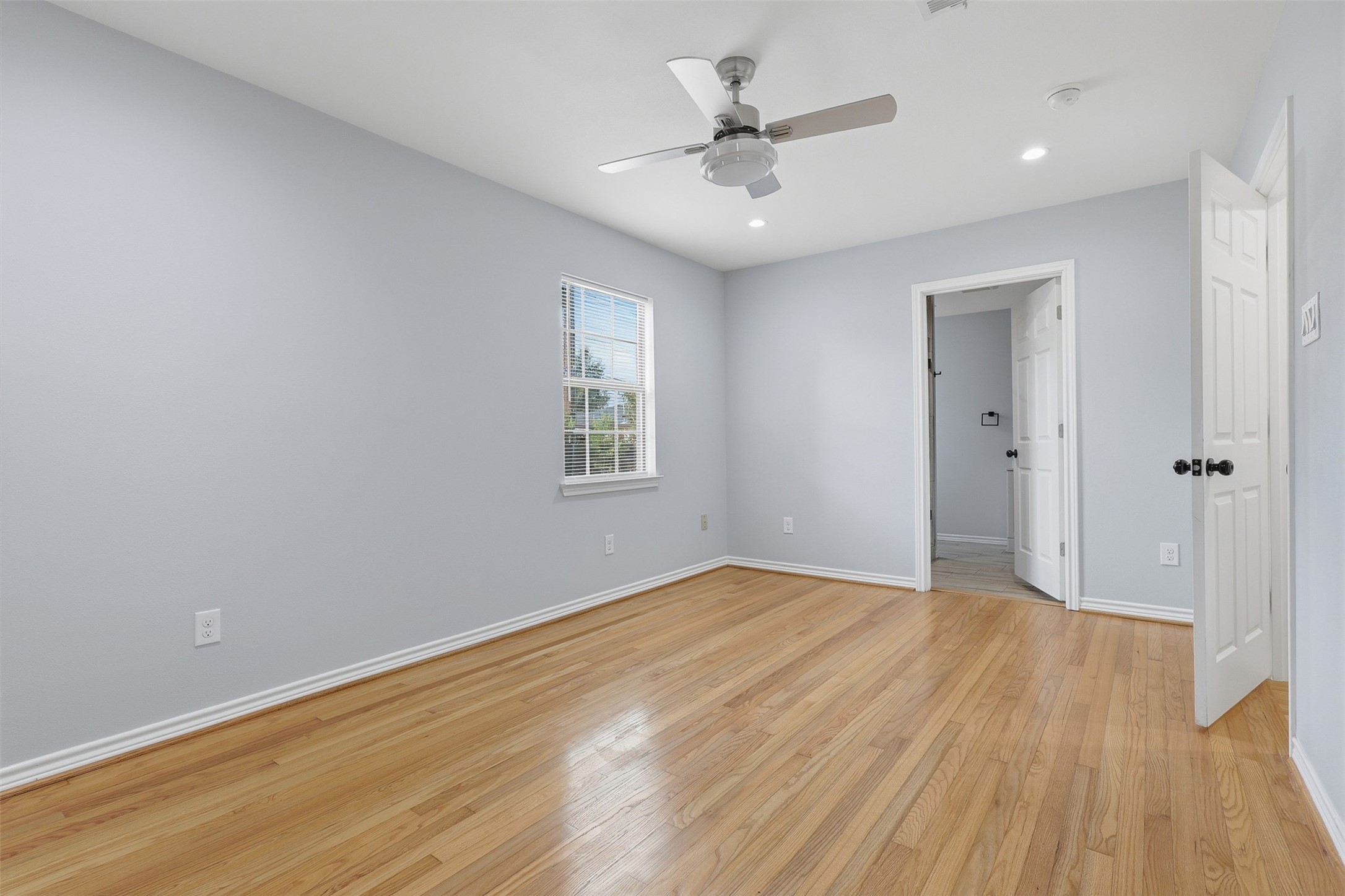 4926 Edfield Street Houston, TX 77033 - Photo 8 of 30 Bright and airy bedroom with hardwood floors, a ceiling fan, and a large window letting in natural light.