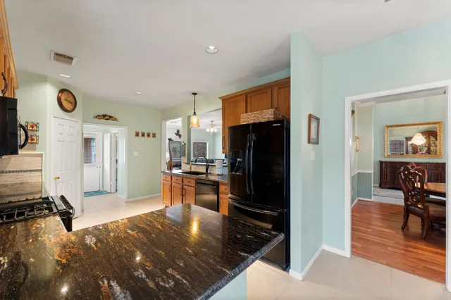 a kitchen with stainless steel appliances a refrigerator a stove a sink a dining table and chairs with wooden floor