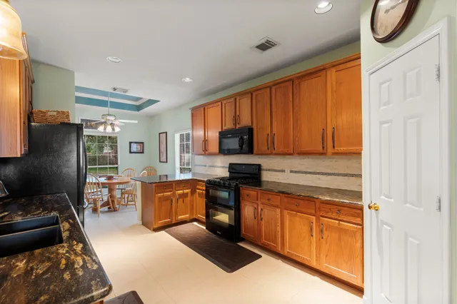 a kitchen with stainless steel appliances granite countertop a stove top oven a sink dishwasher a dining table and chairs with wooden floor