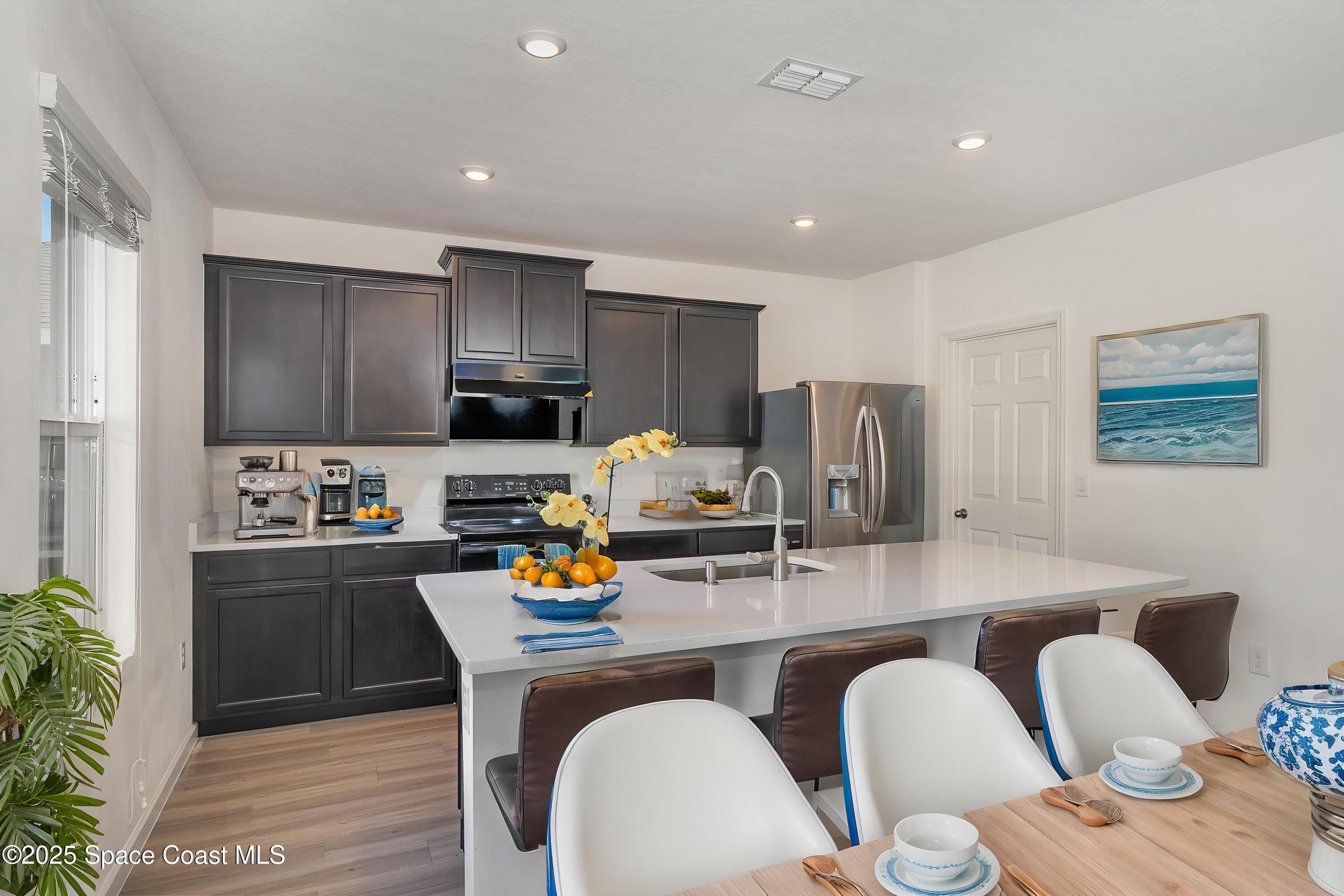1085 Newton Circle Rockledge, FL 32955 - Photo 6 of 34 a kitchen with stainless steel appliances granite countertop a table chairs sink refrigerator and microwave