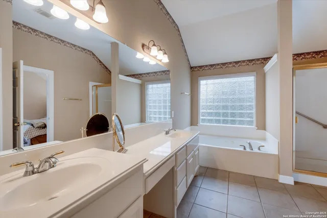 a bathroom with a bathtub a double vanity sink and mirror