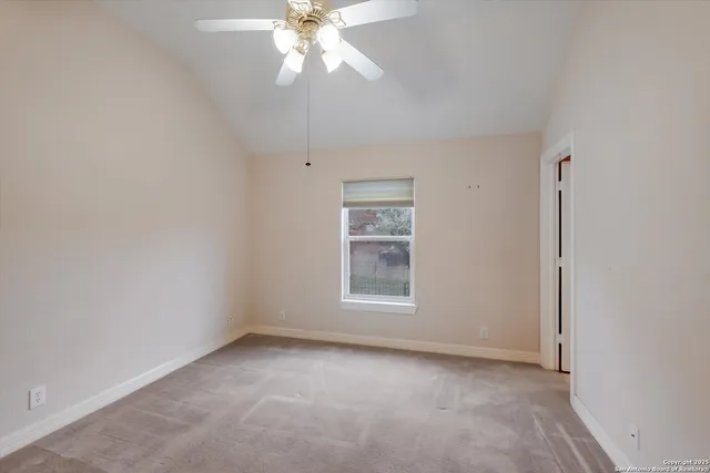 an empty room with a chandelier fan and windows