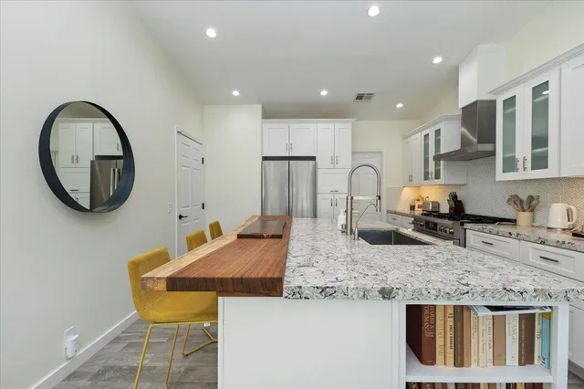 a kitchen with kitchen island granite countertop a sink and a refrigerator