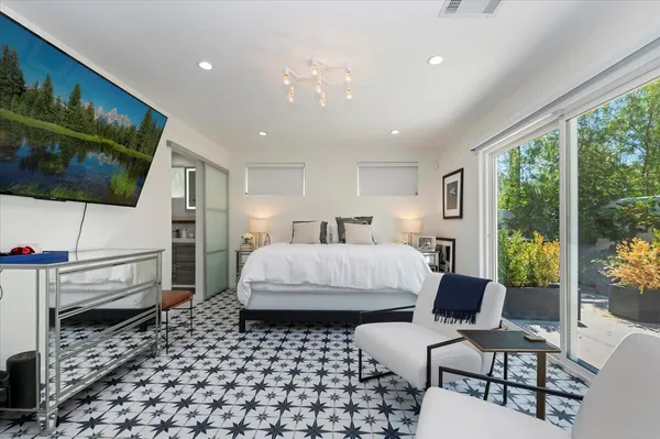 a bedroom with a bed a couch and a flat tv screen next to a large window