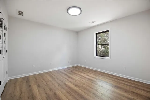 a view of empty room with wooden floor and window