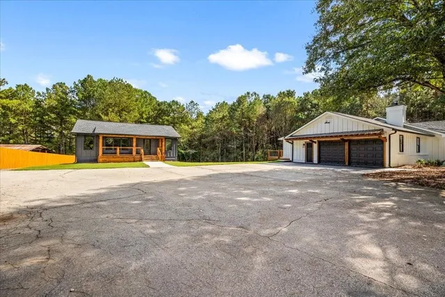 an aerial view of residential house with outdoor space and trees all around
