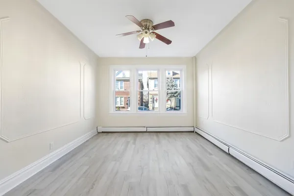 an empty room with wooden floor chandelier fan and windows