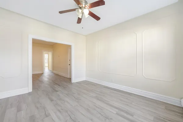 an empty room with wooden floor closet and windows