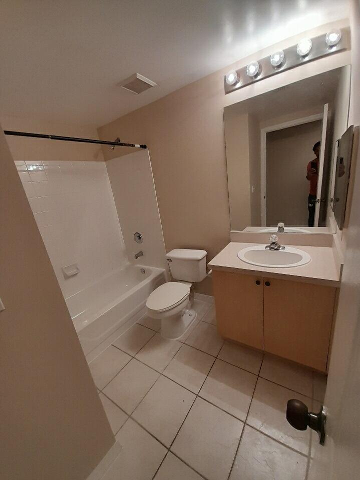 10336 Fox Trail Road South, Unit 1306 Royal Palm Beach, FL 33411 - Photo 2 of 10 a bathroom with a sink a toilet and mirror