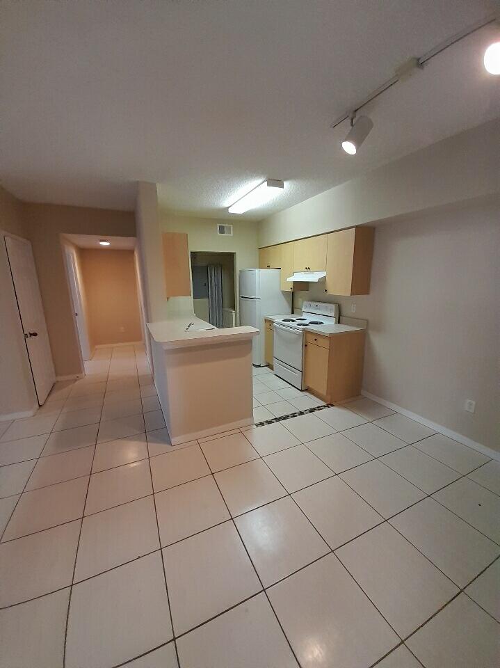 10336 Fox Trail Road South, Unit 1306 Royal Palm Beach, FL 33411 - Photo 3 of 10 a kitchen with stainless steel appliances a sink stove and cabinets
