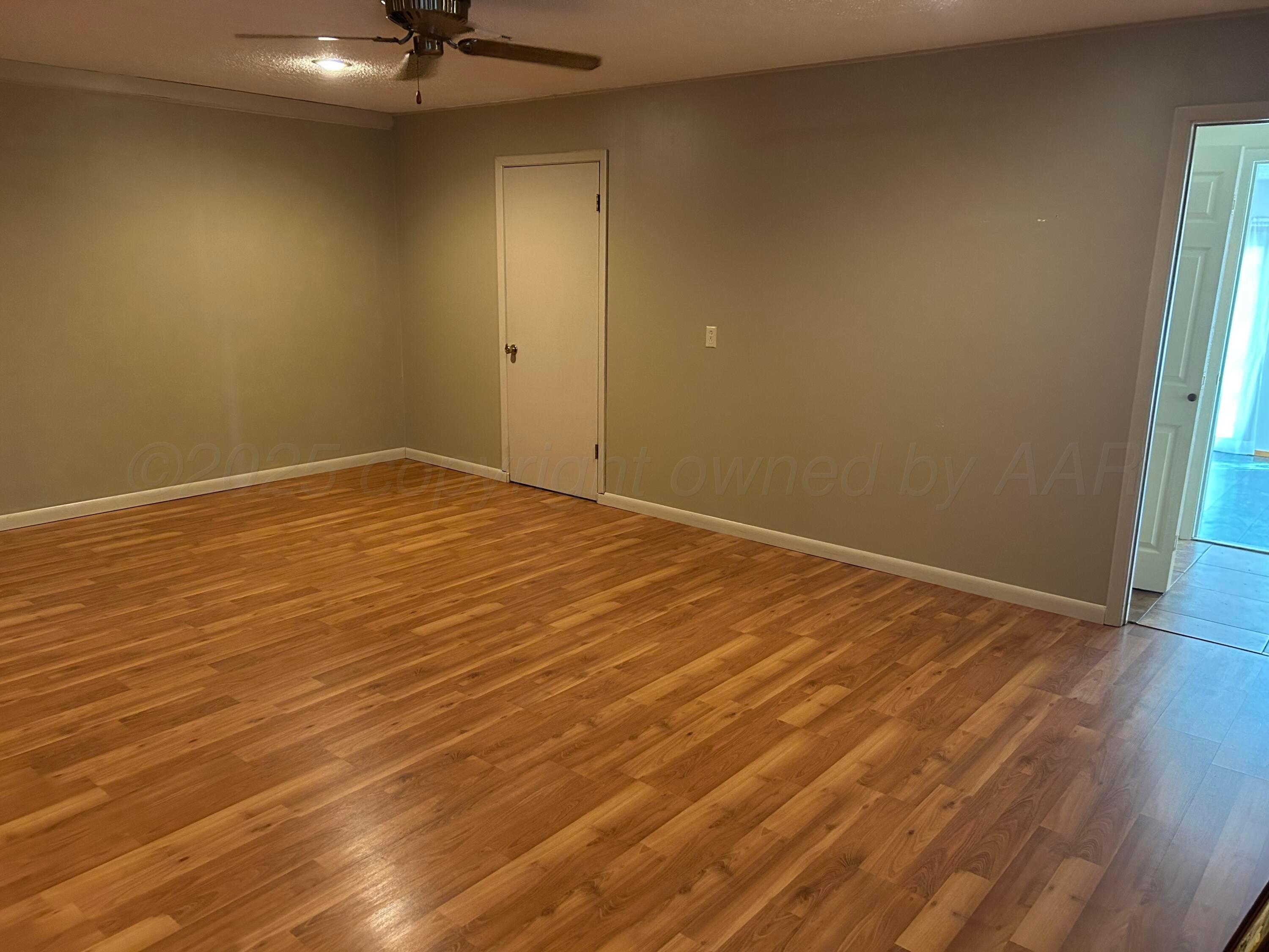 613 South Fulton Street Stratford, TX 79084 - Photo 4 of 15 an empty room with a wooden floor and windows