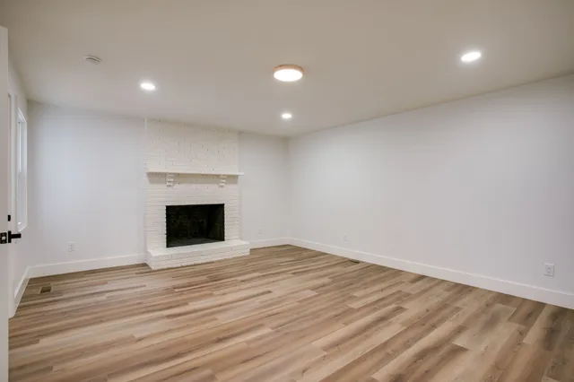 a view of empty room with wooden floor and fireplace