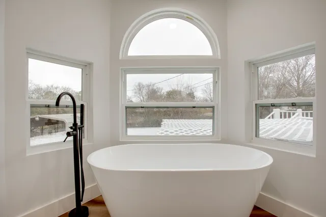 a white bath tub sitting in a bathroom next to a window