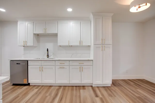 a kitchen with white cabinets and sink