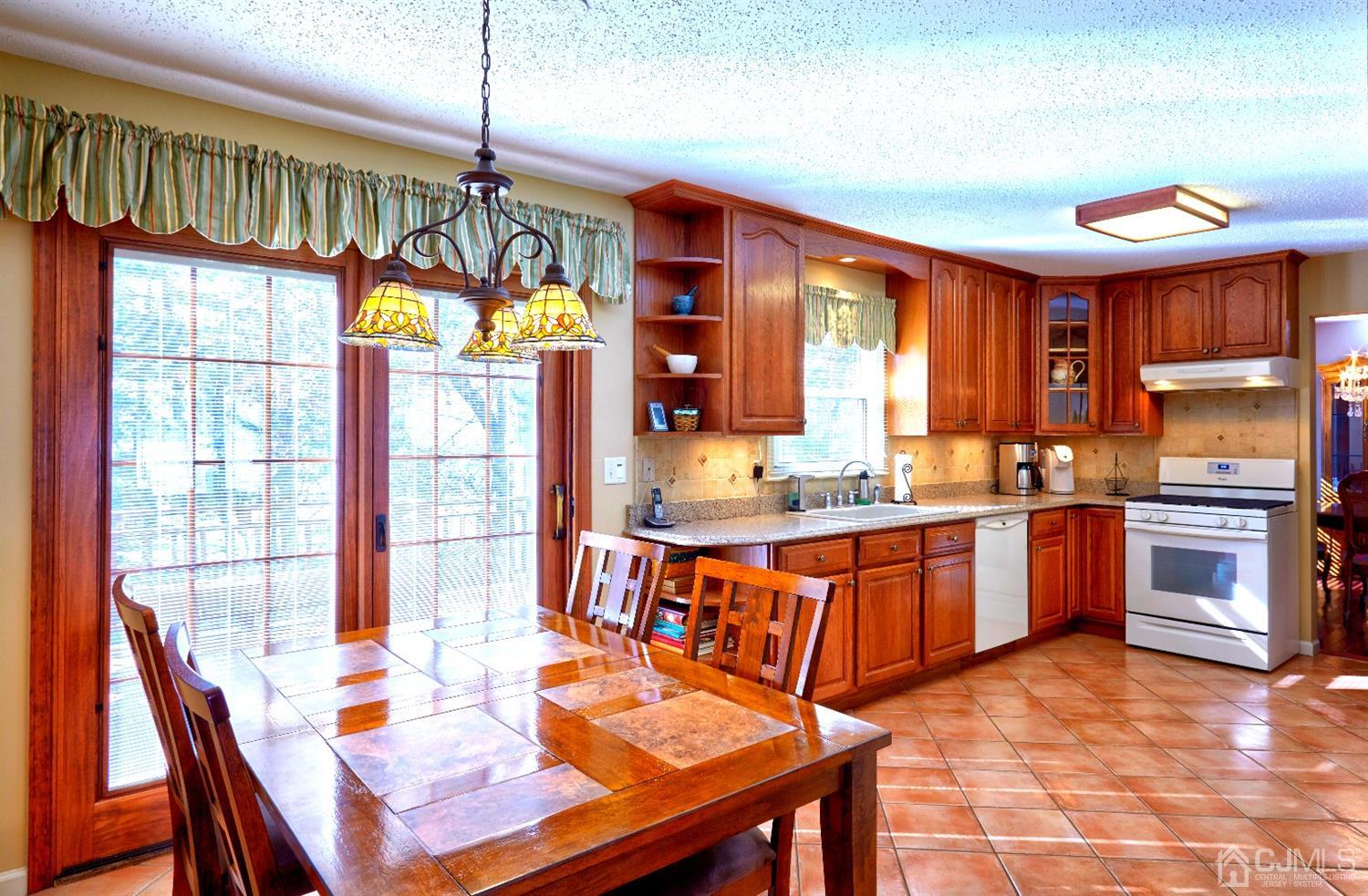 21 Aqueduct Place Howell, NJ 07731 - Photo 5 of 44 a open kitchen with stainless steel appliances granite countertop a stove a sink dishwasher a dining table and chairs with wooden floor