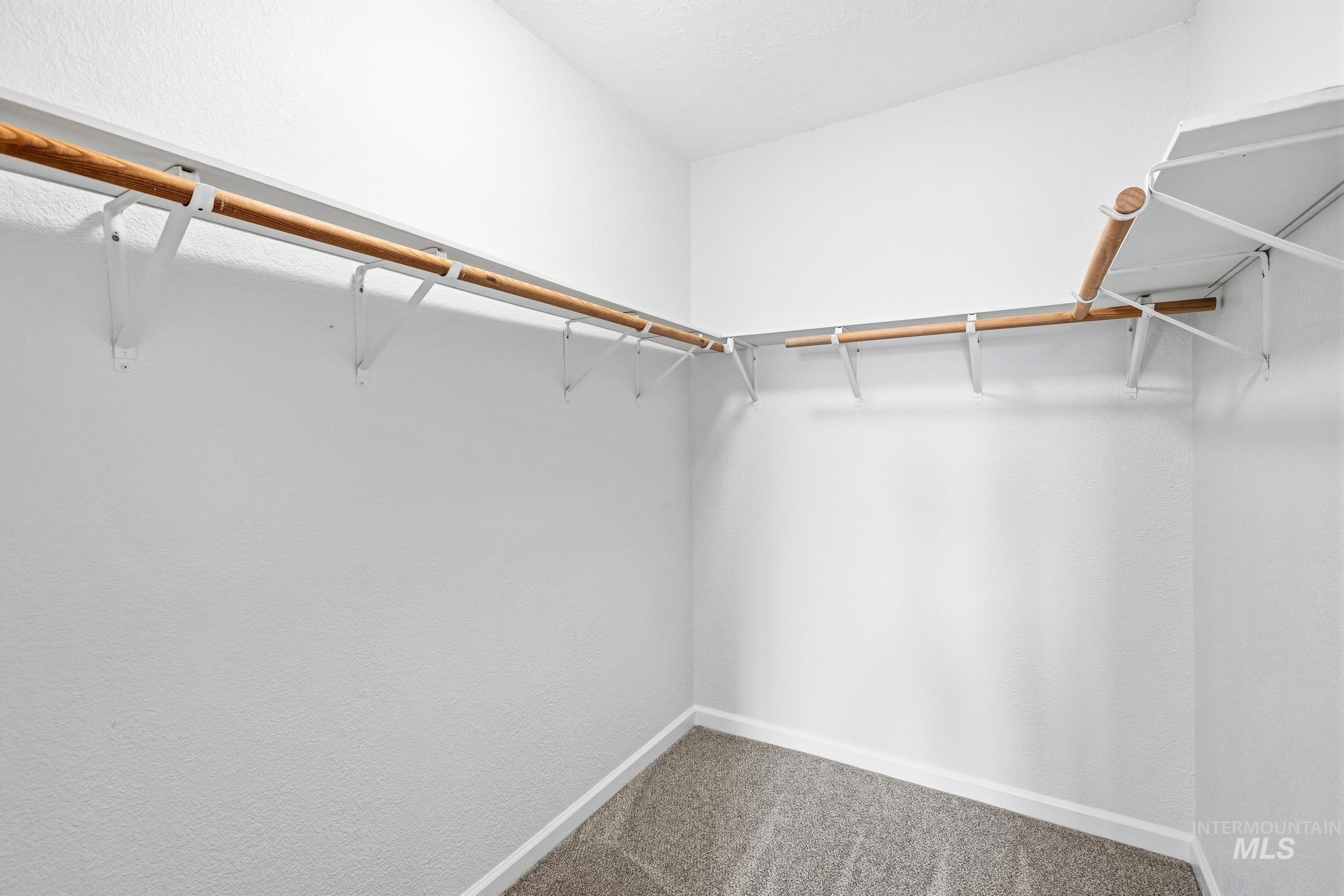 14666 Willis Road Caldwell, ID 83607 - Photo 27 of 50 Walk-in closet featuring light wood-finish hanging rods, white shelving, white walls, and gray carpet flooring