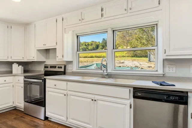 a kitchen with white cabinets and a window