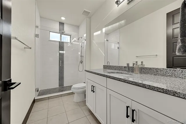 a bathroom with a granite countertop sink a toilet and a shower