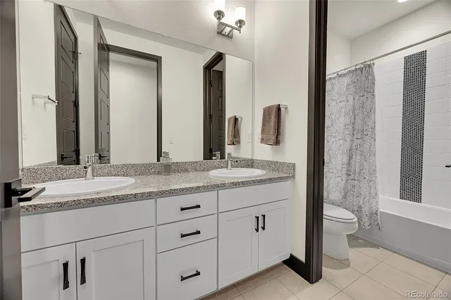 a bathroom with a granite countertop sink a toilet a large mirror and shower