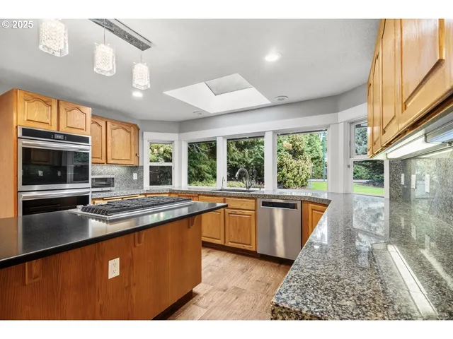 a kitchen with stainless steel appliances granite countertop a stove a sink and a microwave