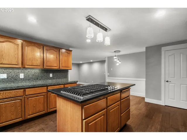 a kitchen with stainless steel appliances granite countertop a stove a sink dishwasher and cabinets with wooden floor