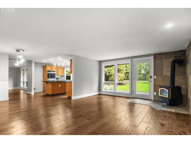 a view of an empty room with window and wooden floor