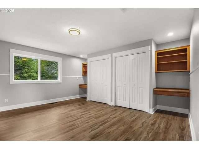 an empty room with wooden floor cabinet and windows