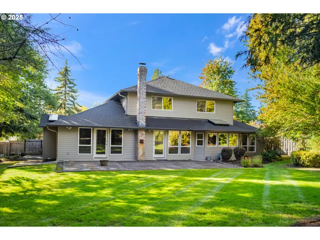 a view of a house with a big yard potted plants and large tree
