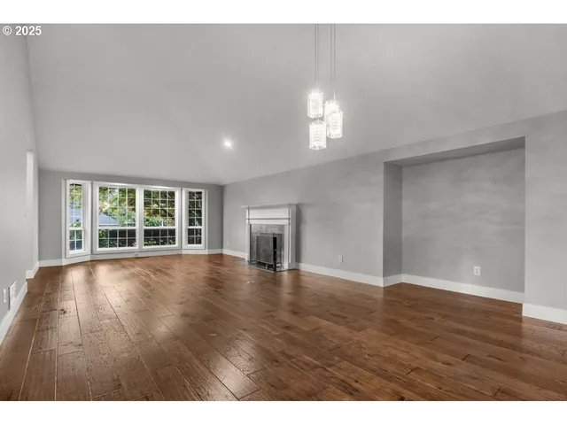 a view of empty room with wooden floor and fireplace