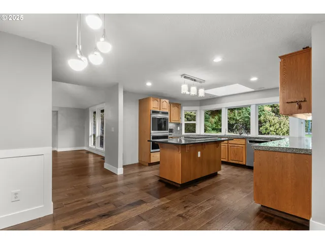 a view of living room with kitchen island wooden floor and windows