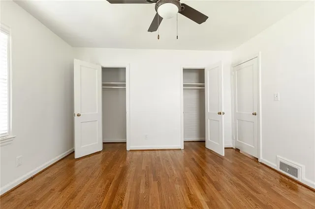 an empty room with wooden floor closet and windows