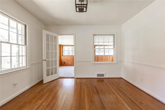 an empty room with wooden floor and windows