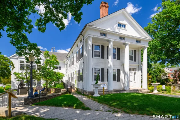 a view of a white house with a yard and plants