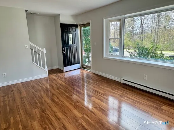 a view of an empty room with wooden floor and a window