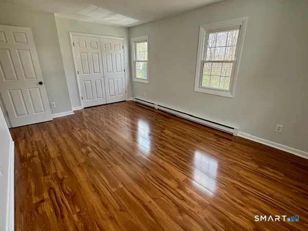 an empty room with wooden floor and windows