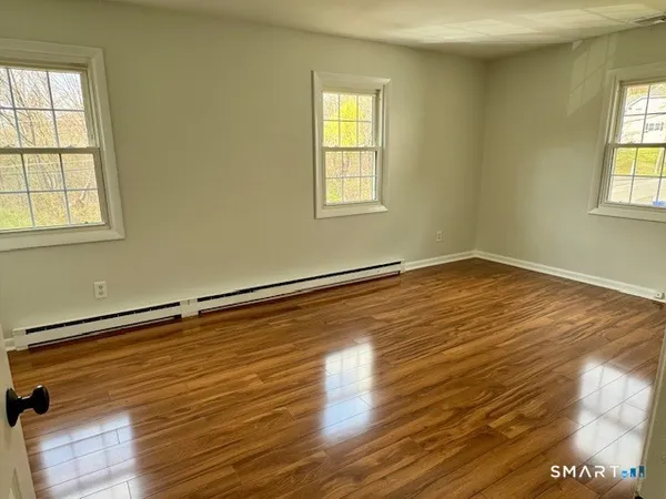 a view of empty room with wooden floor and fan
