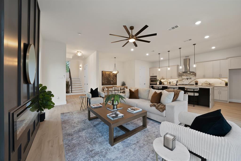 1415 Fayette Street Dallas, TX 75203 - Photo 2 of 40 Open-concept living area featuring wood-finish flooring, a contemporary kitchen with a large island, stainless steel appliances, and pendant lighting