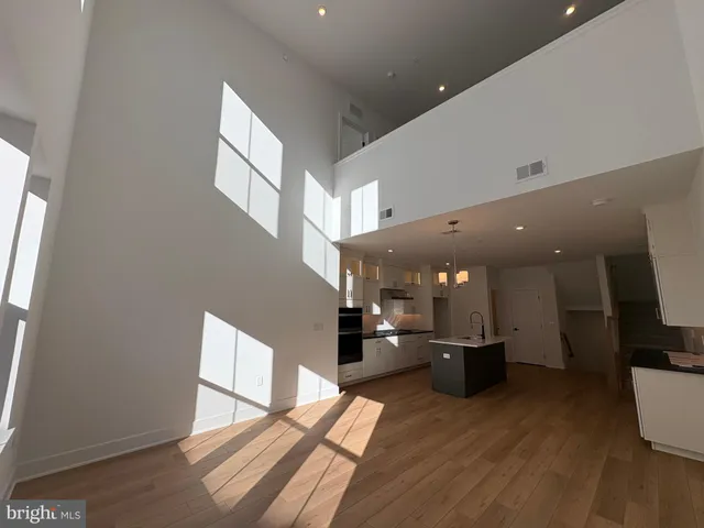 a living room with stainless steel appliances kitchen island furniture and a wooden floor