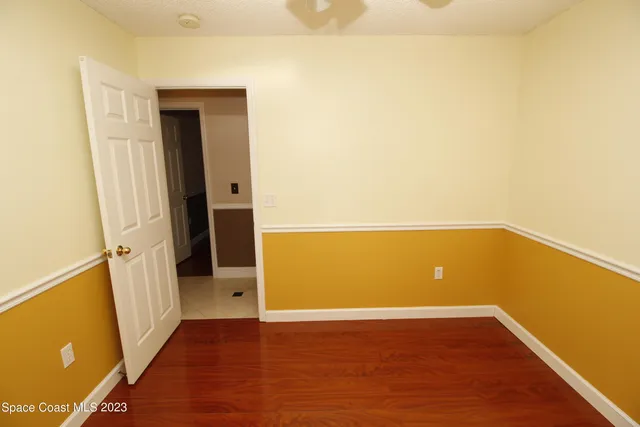 an empty room with wooden floor and entrance